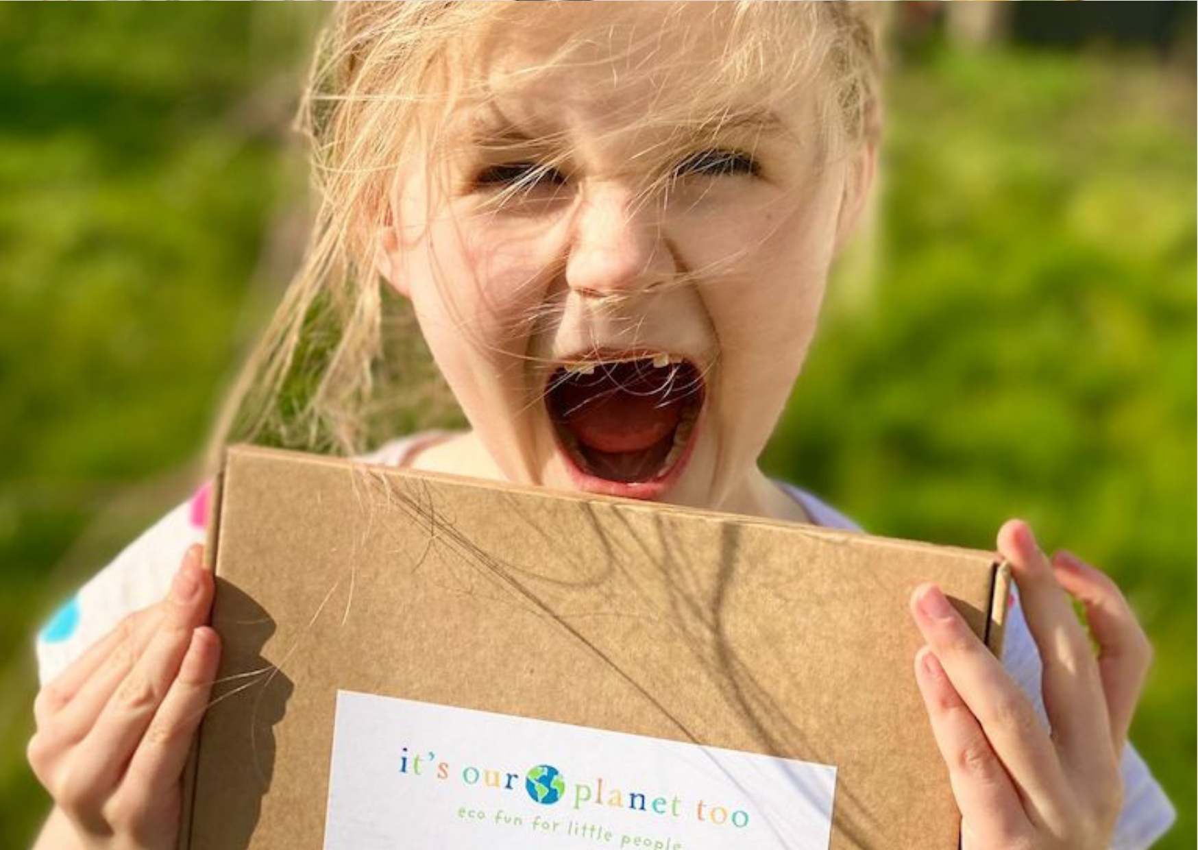 A girl smiles with her It's Our Planet Too Box