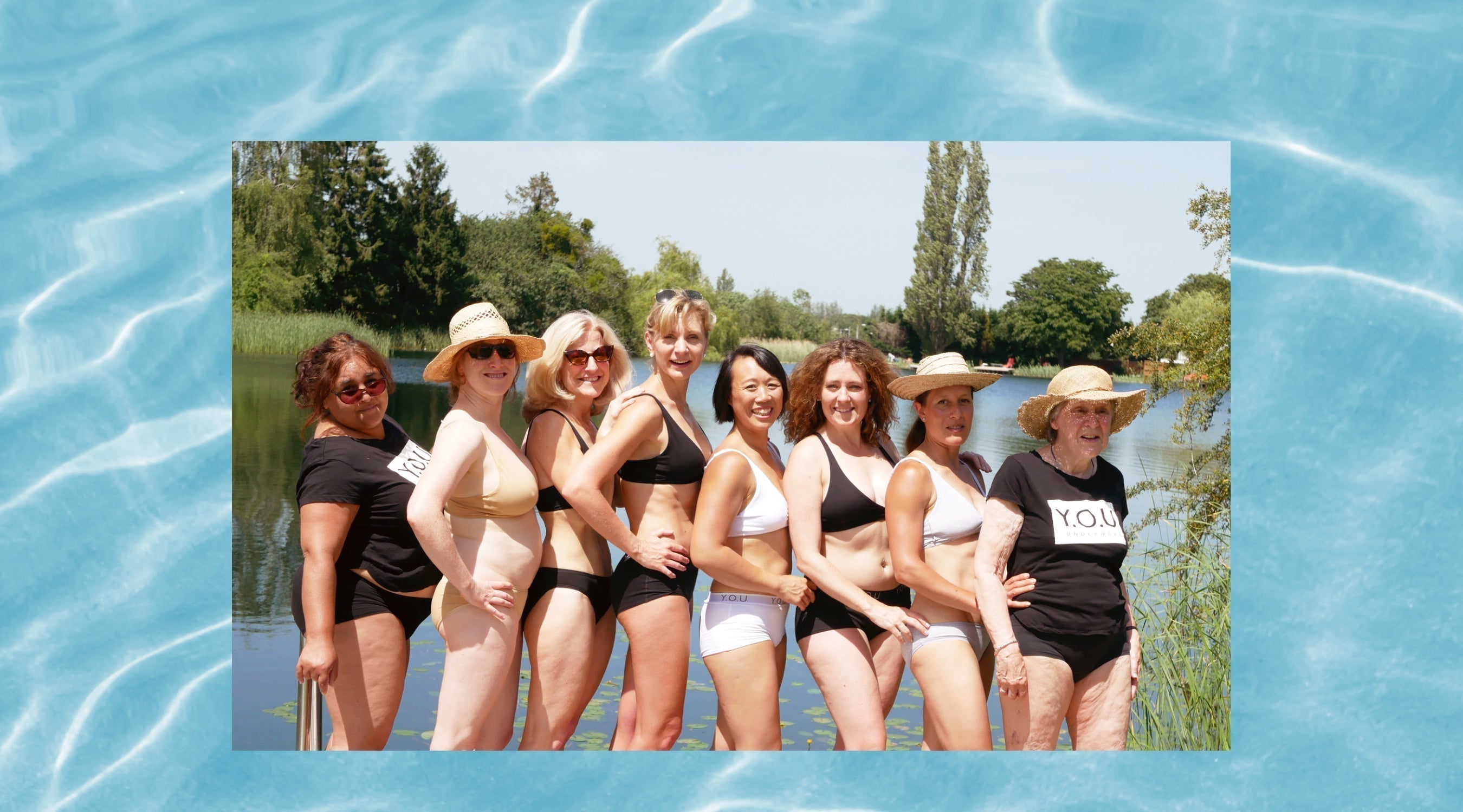 Photo of eight women standing together and posing in front of a lake with trees around the outside. They are all wearing black, white, or almond coloured Y.O.U organic cotton matching underwear sets and stand side on with their hands on their hips.