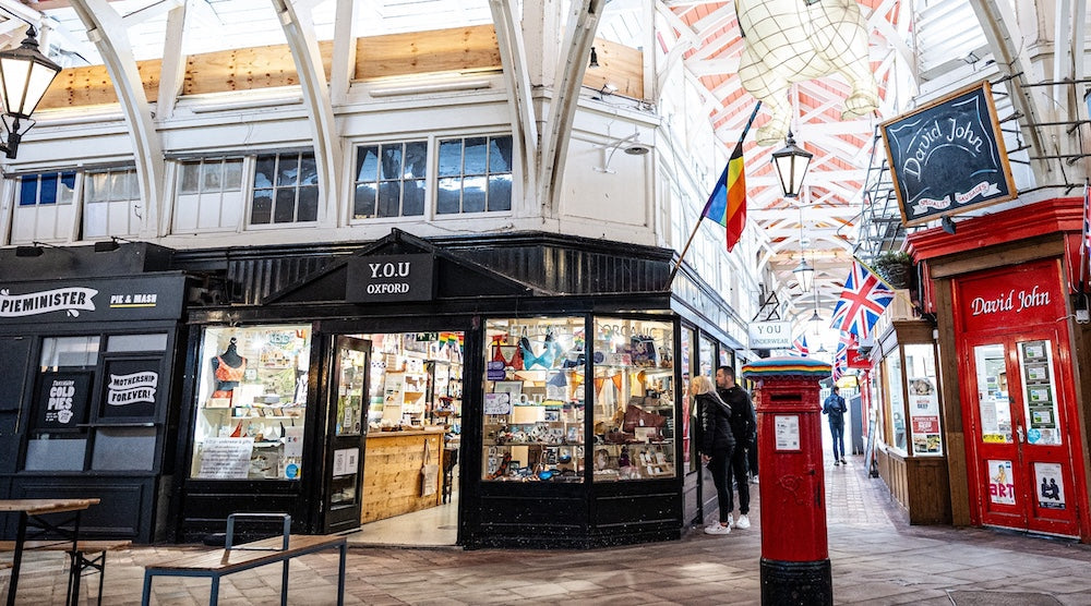 exterior of the YOU Oxford shop inside the Oxford covered market with Pieminister and the butcher shop on either side.