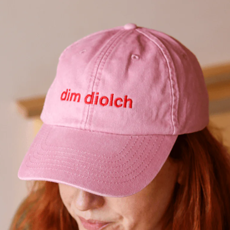 A model wearing the Black & Beech Dim Diolch baseball cap in pink