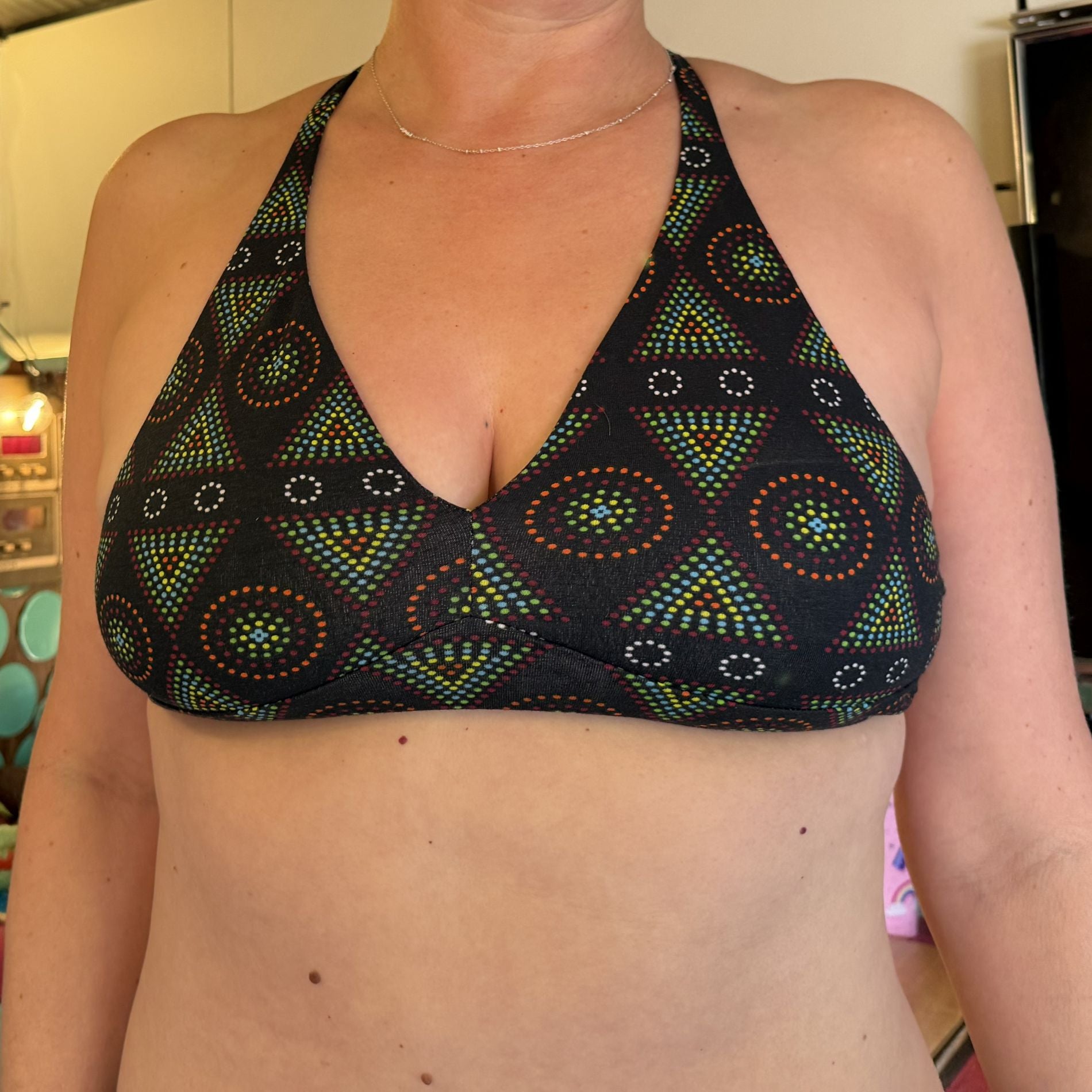Close-up image of a a model wearing the YOU Underwear Black Mara Bralette. They are facing the camera and the image is cropped below the models chin and above the belly button.
