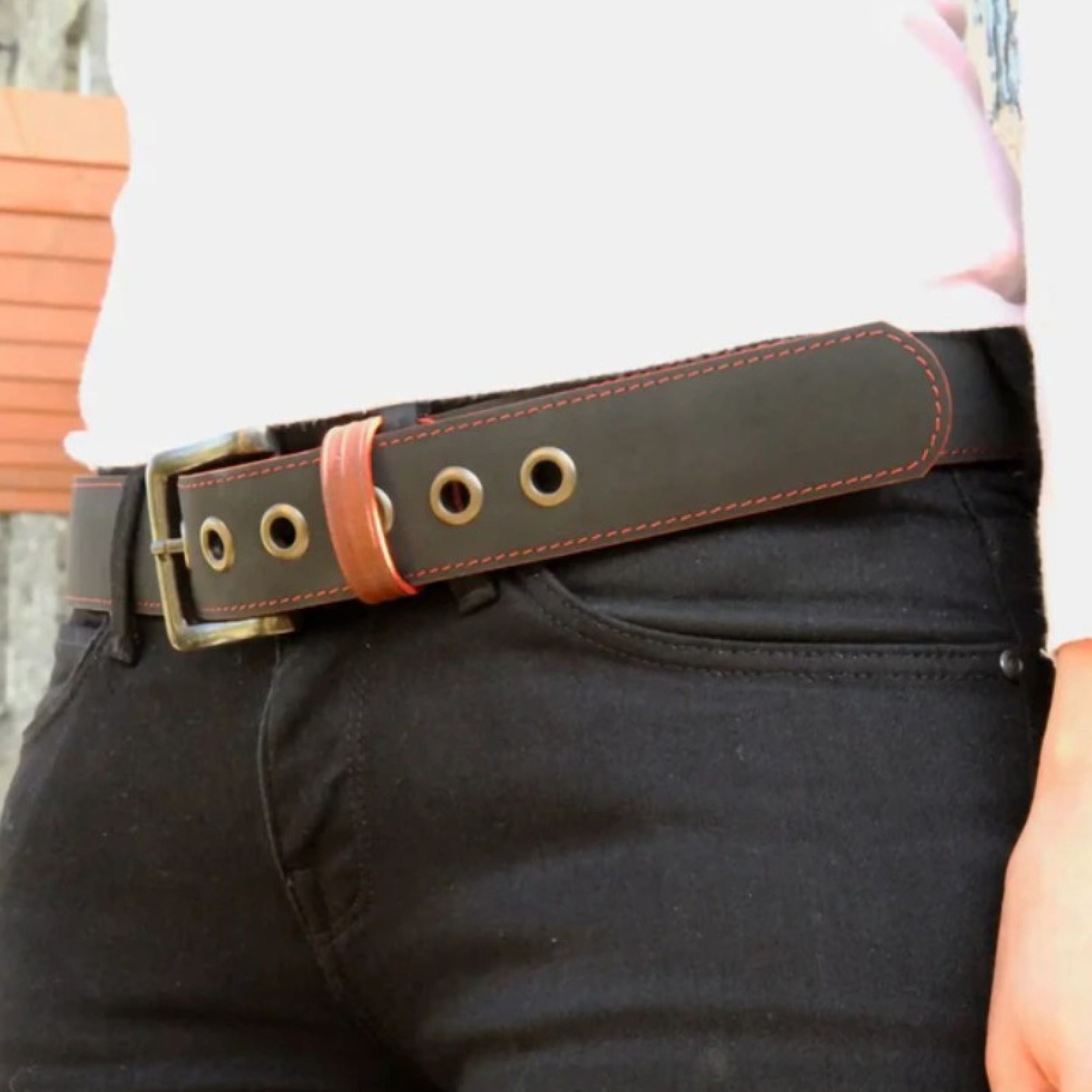 A close up photo of a model wearing the Elvis & Kresse black printing blanket belt paired with a white t-shirt and black jeans.