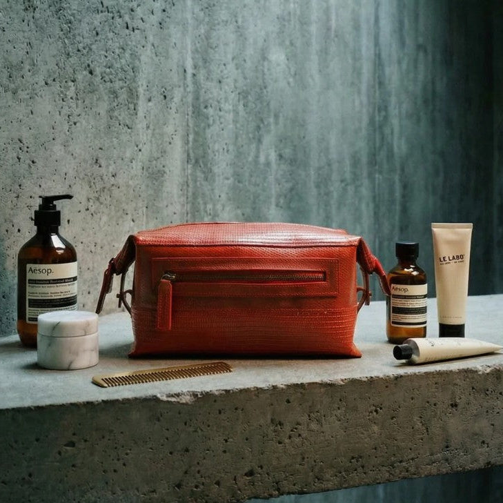Elvis and Kresse red large wash bag in a stone bathroom with skincare products set around it