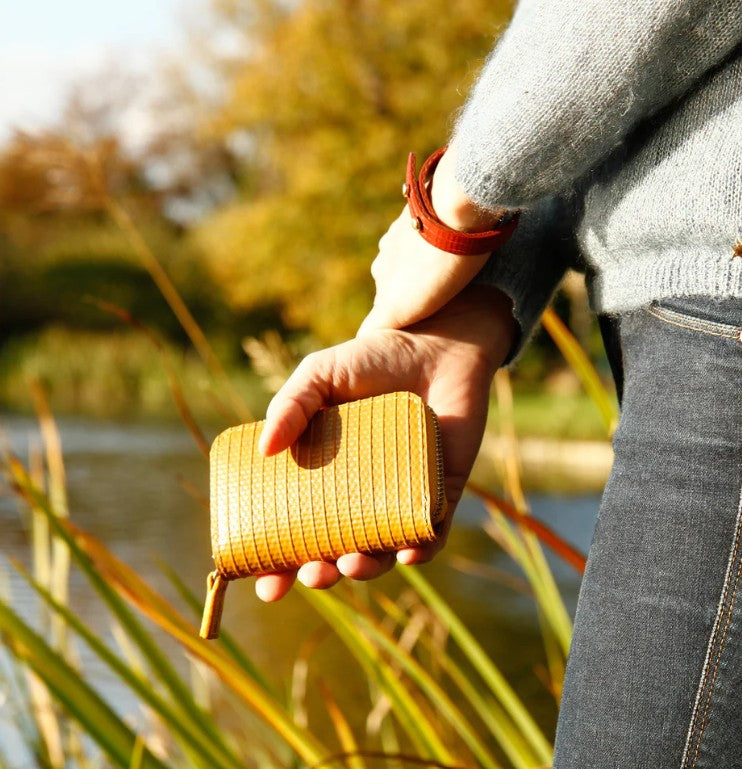 A model holding the Elvis and Kresse yellow coin pouch by the side of lake