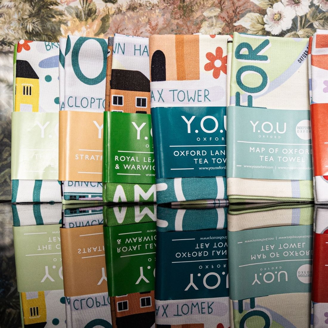 Organic cotton tea towels printed with illustrated designs of different cities all folded and displayed together.