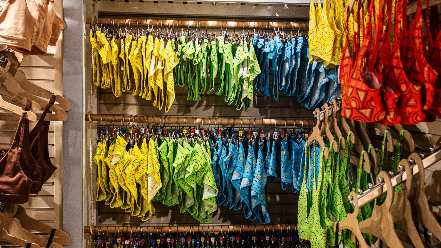 A photo of the YOU Underwear rails in a shop. The rails are full of bright red, yellow, green and blue underwear which is neatly hung up.