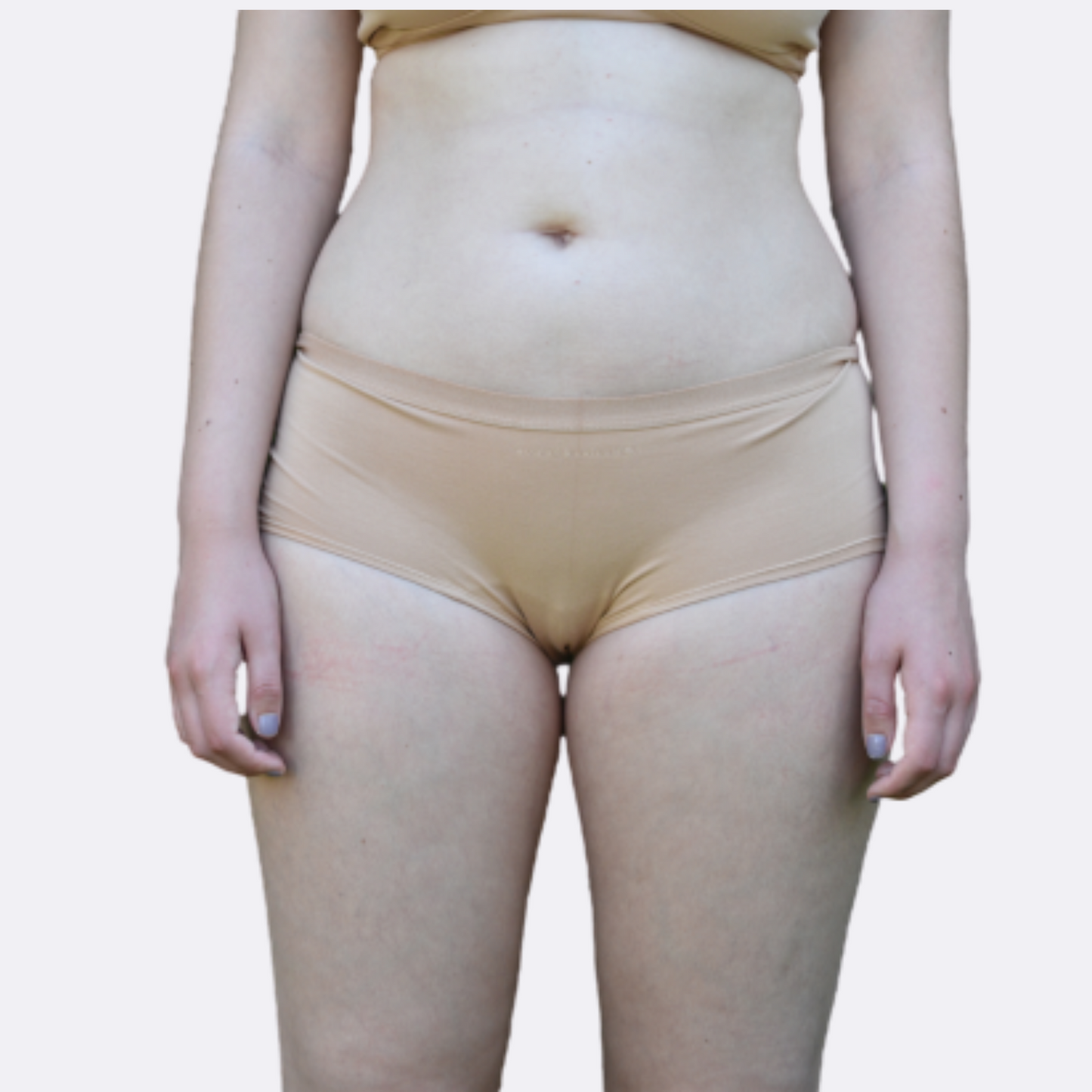 Model with light skin and purple nail polish wears organic cotton plain almond light nude boy shorts