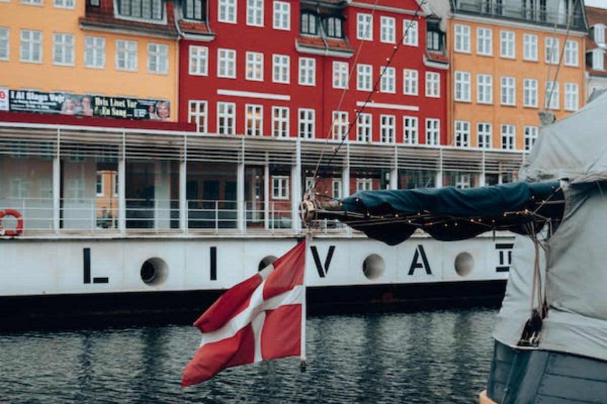 A Danish flag blowing in the wind over a canal