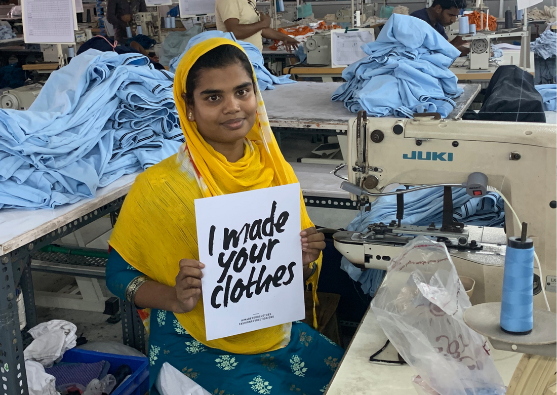 A garment worker in yellow and blue holds a sign saying 'I made your clothes'