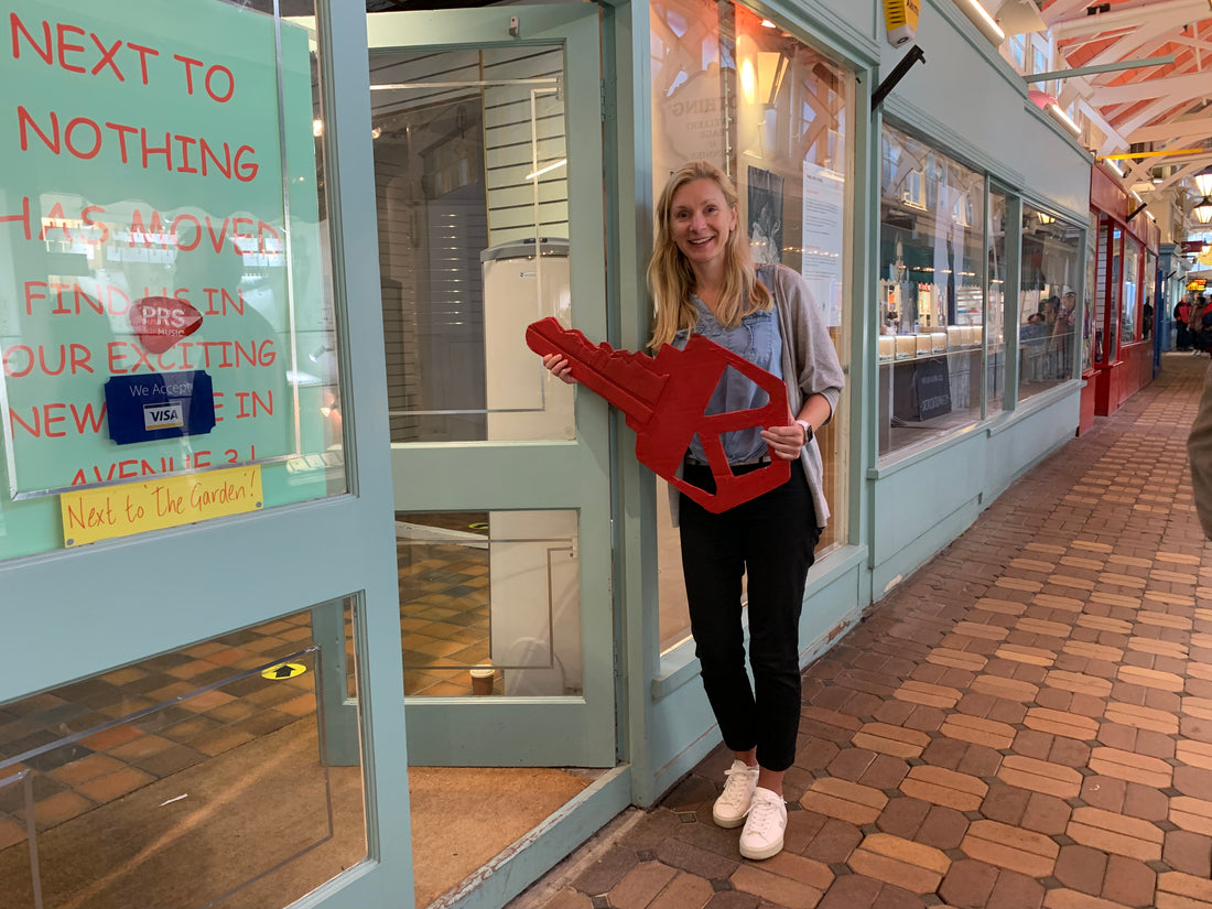 Sarah holding a giant red key outside of the new shop