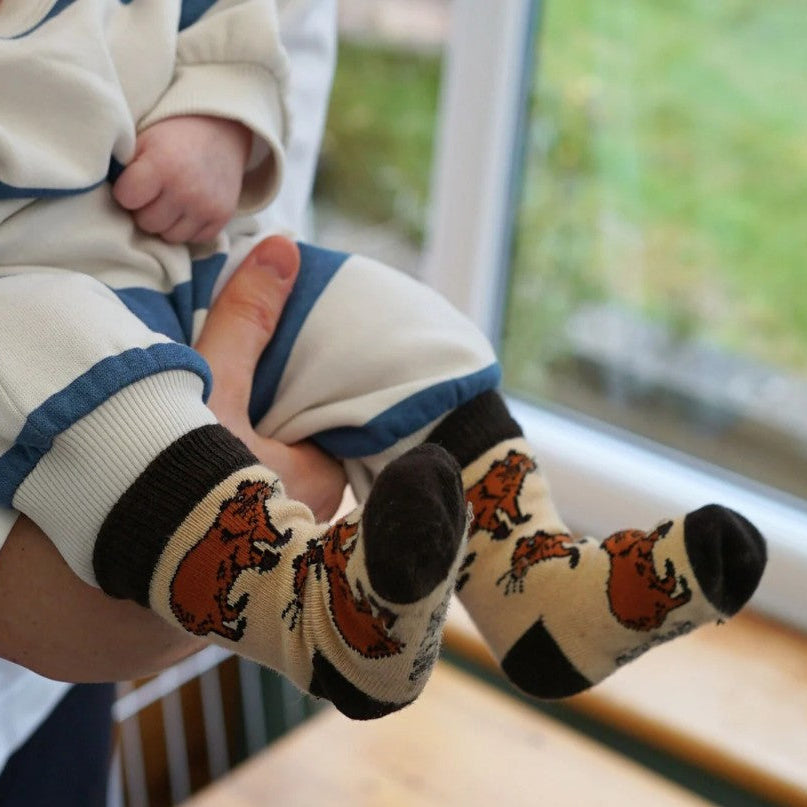 A photo of a child wearing the Bare Kind capybara socks whilst being held by their parents