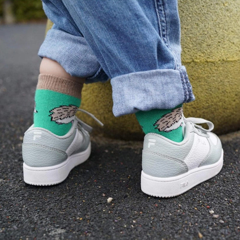 A photo of a child wearing the bare kind hedgehog socks with grey trainers and blue jeans