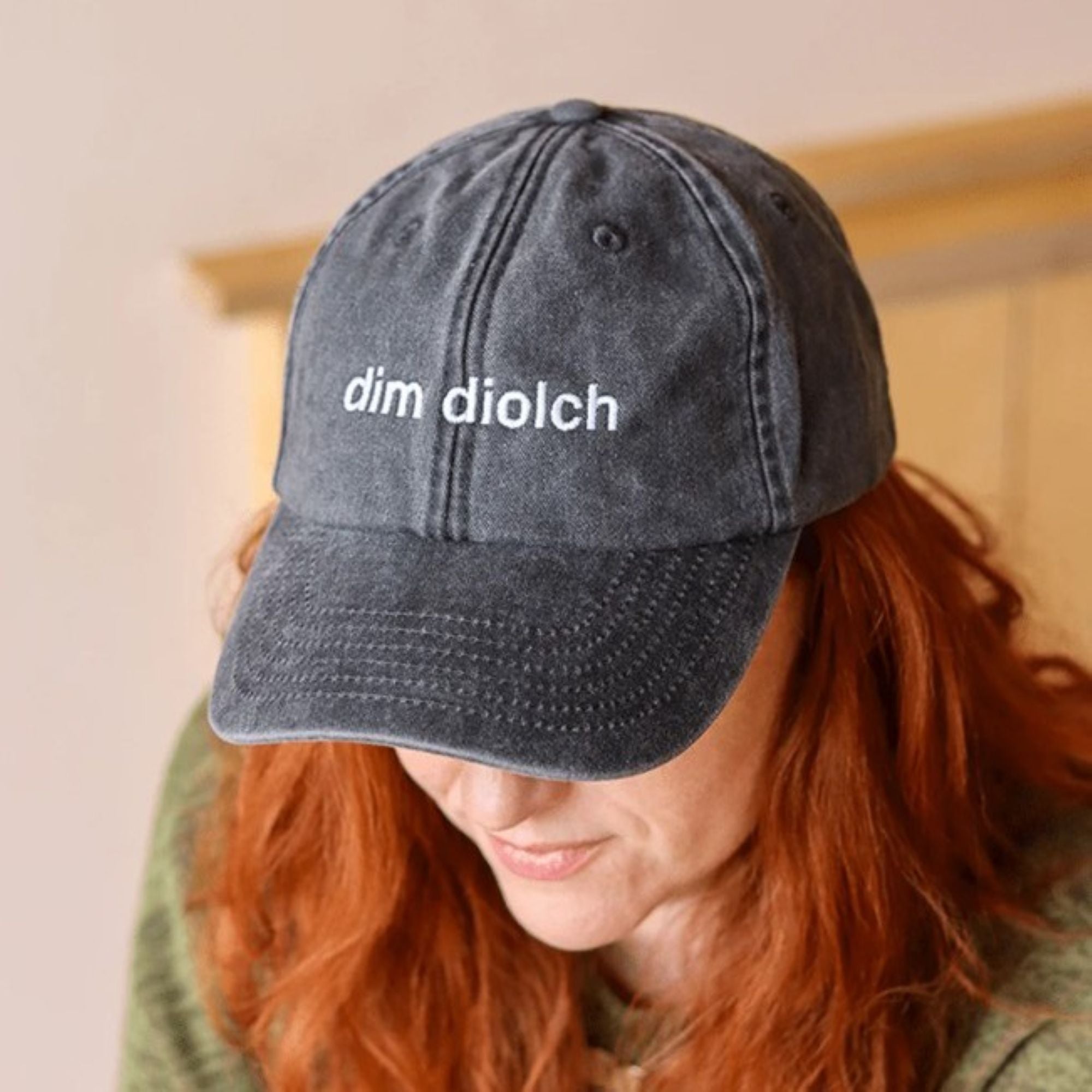 A model wearing the Black & Beech Dim Diolch baseball cap in acid black 