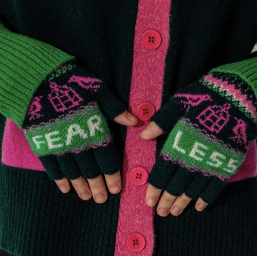 A close up photo of a model wearing the Black & Beech fearless gloves. The model is also wearing a dark green and bright pink knitted cardigan. 