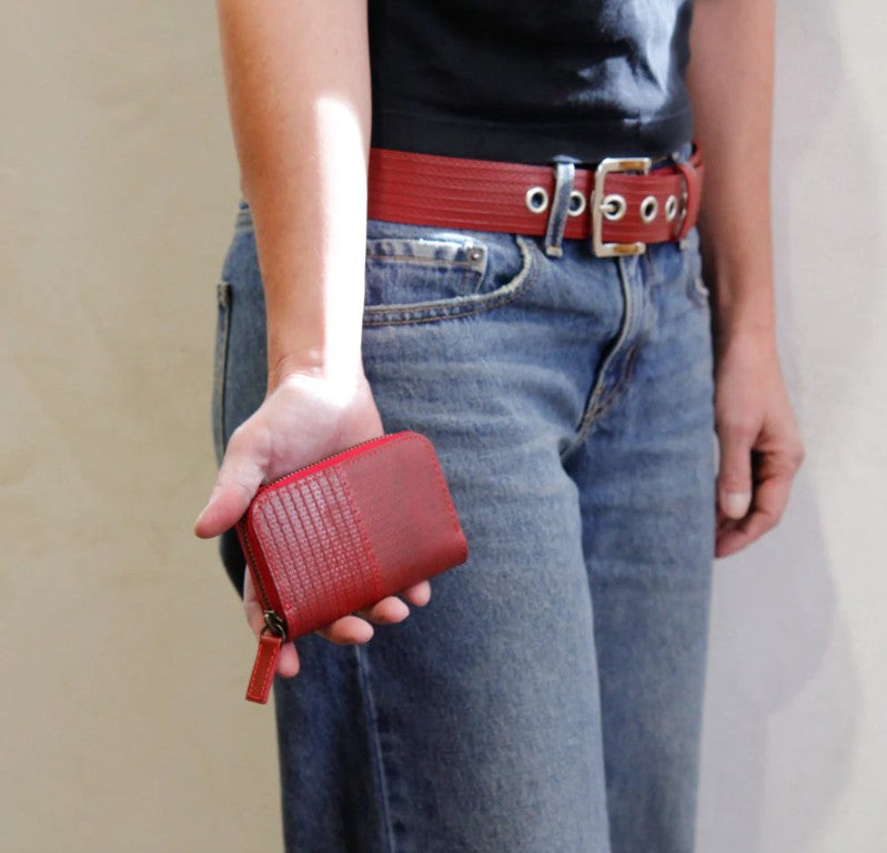 A woman holding the Elvis and Kresse red coin pouch wearing blue jeans