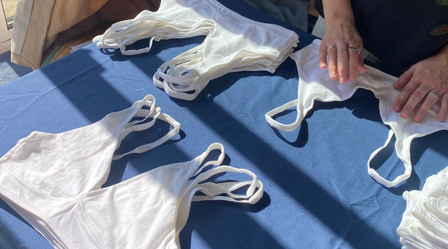 a table with a blue tablecloth with white bralettes laid out as someone sorts them