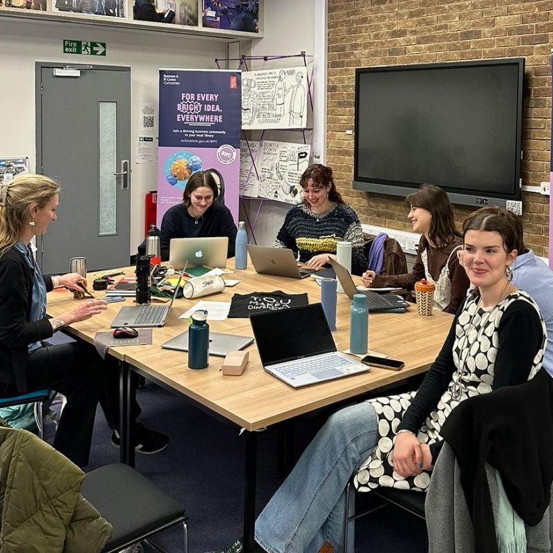 the YOU team working around a desk together.