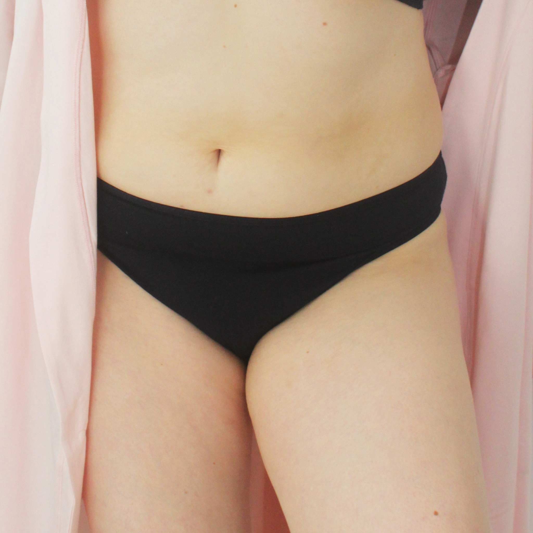 A cropped image of a person’s midsection wearing black bikini bottoms and a pink robe draped loosely around them. The person's belly button is visible, and the focus is on the clothing and lower torso.