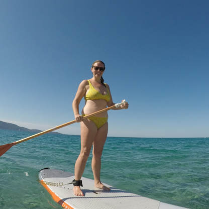 Frances wears our yellow mara bikini and bralette matching organic cotton underwear set on a paddle board in the sea