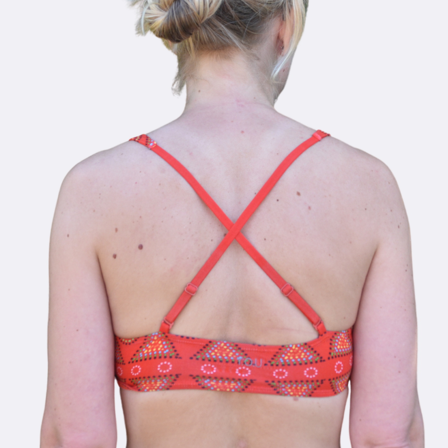 A light skinned woman wears an organic cotton red mara Bralettes  - back view with crossed straps