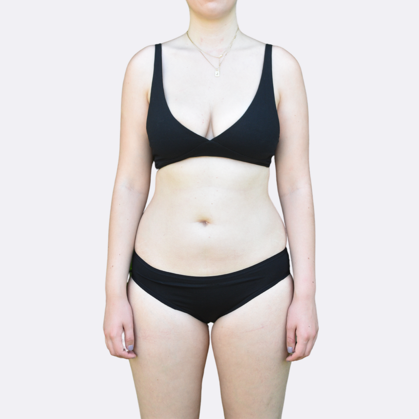 A light skinned woman wears the organic cotton Black bralette and bikini set facing the front